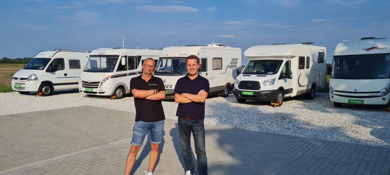 Jan und Alex vor einer Reihe Wohnmobile